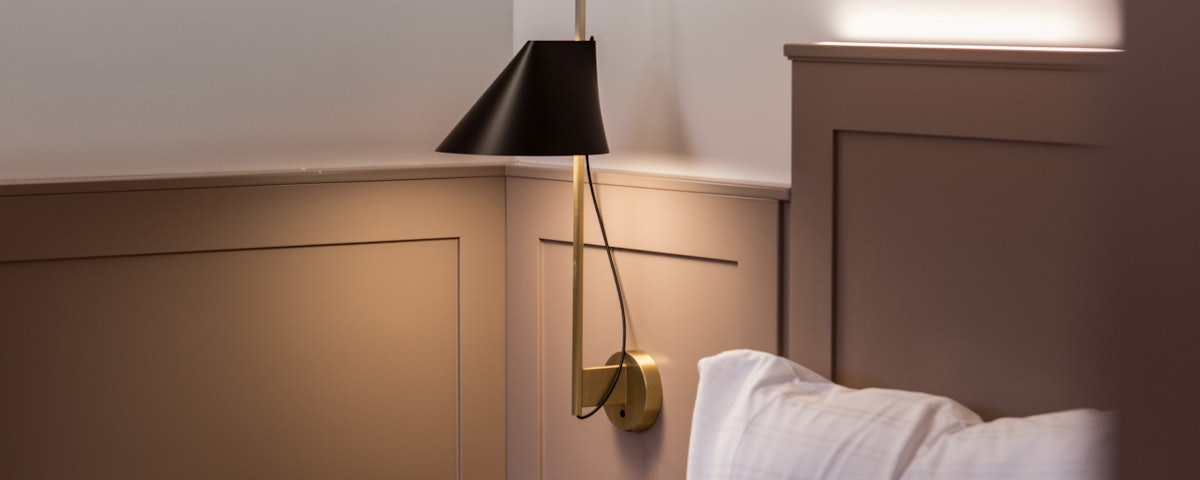Yuh Wall Lamp on a bedside wall in a bedroom setting