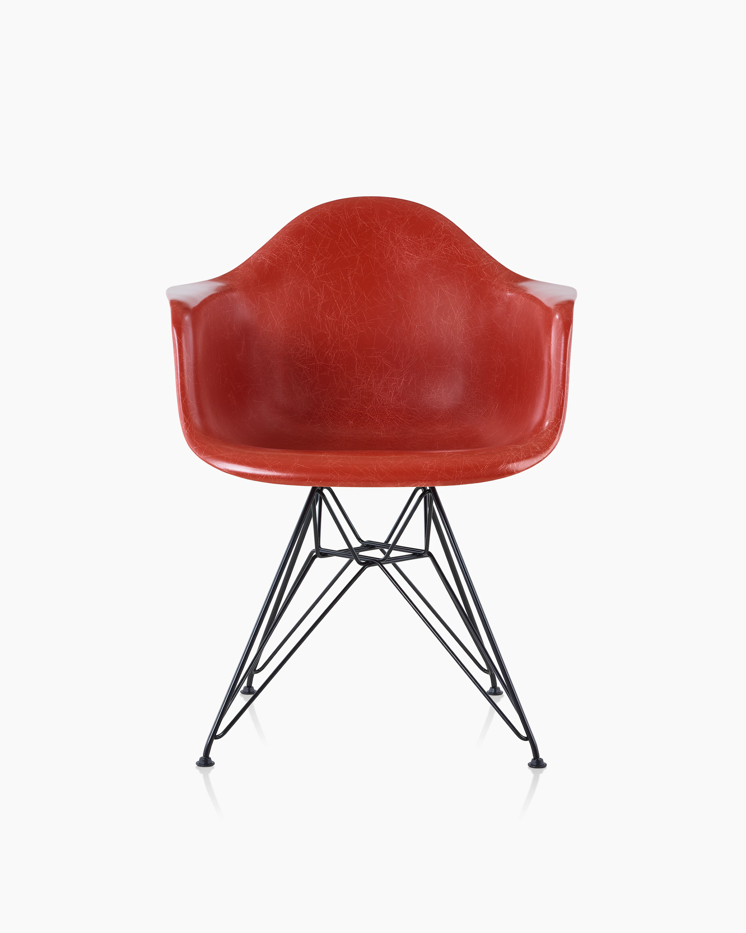 A red Eames Molded Fiberglass Chair with arms and a wire base, viewed from the front.