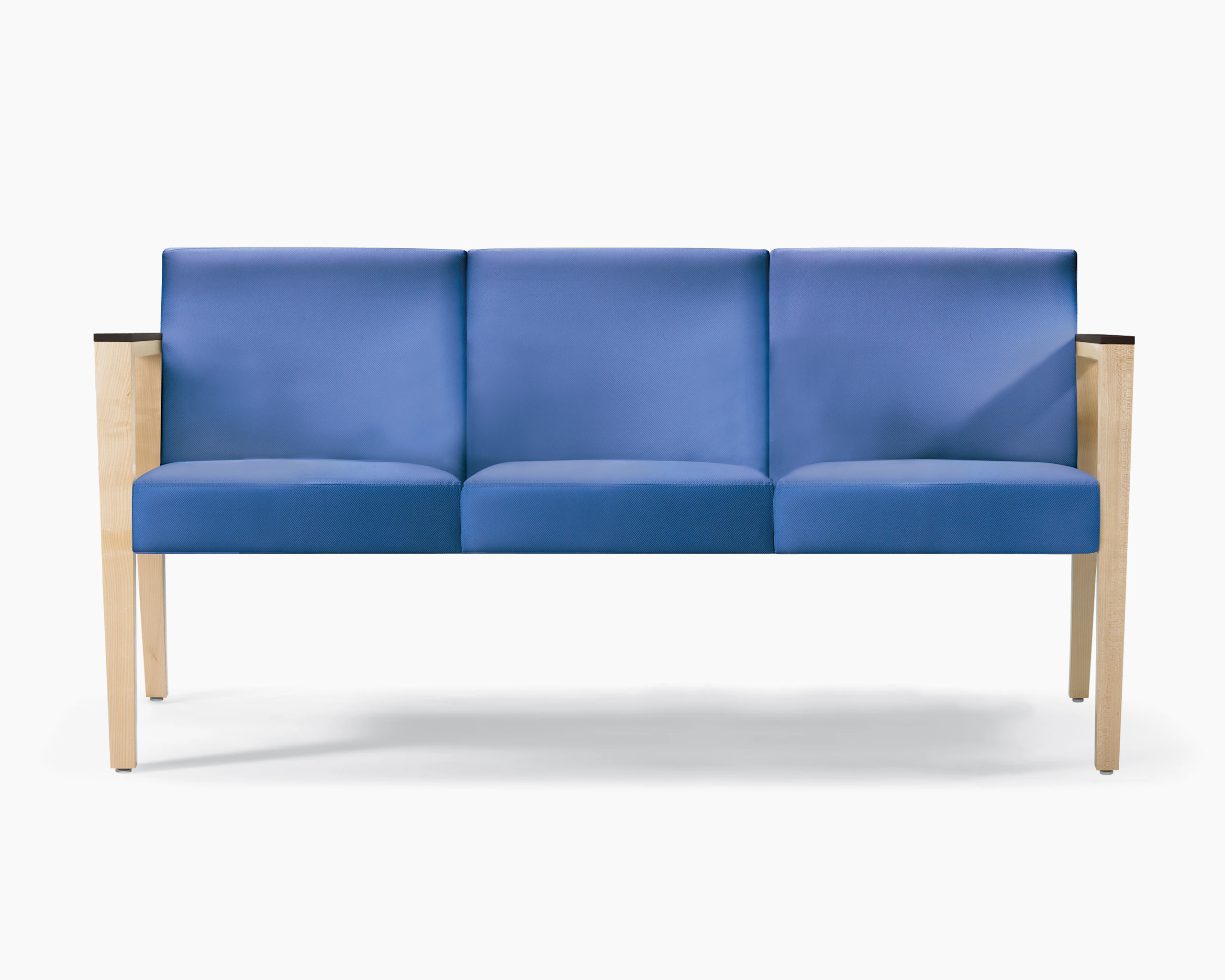 A front view of a Brava 863 Sofa in blue textile with maple base and urethane arm caps.