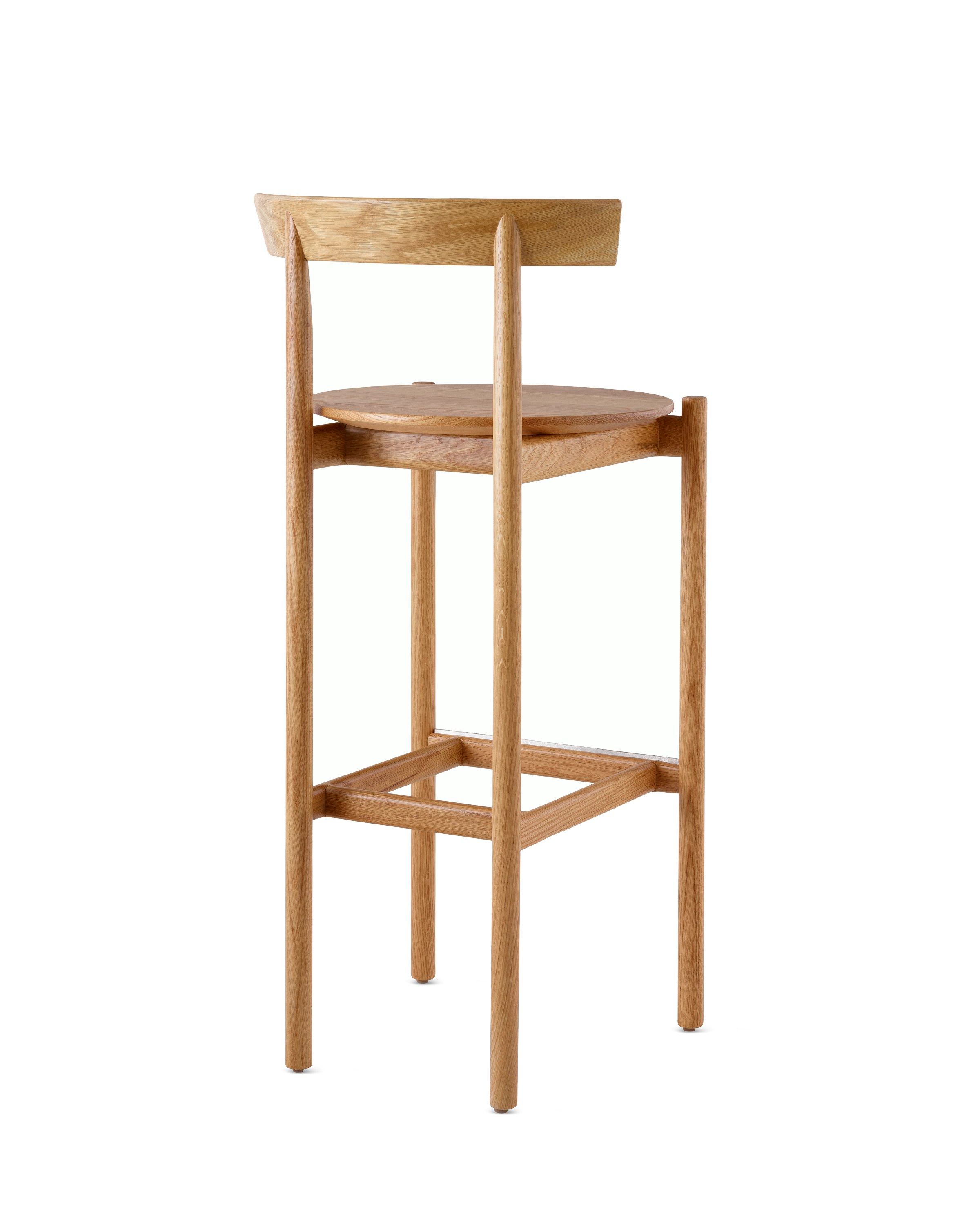 An oak bar-height Comma Stool, viewed from the back at an angle.