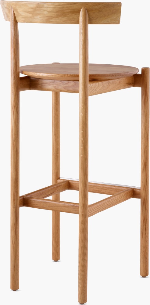 An oak bar-height Comma Stool, viewed from the back at an angle.