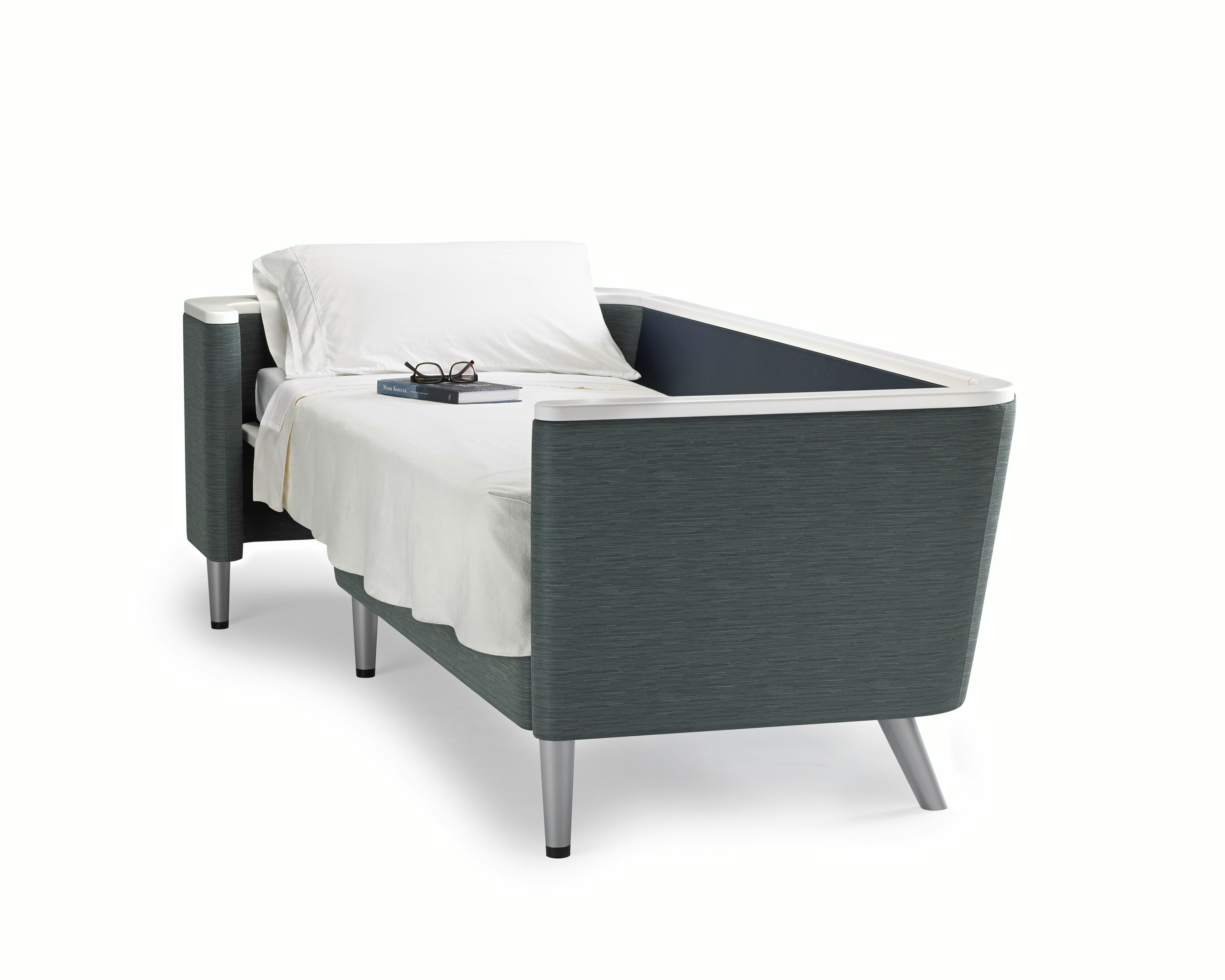 A Palisade Flop sofa converted to sleep surface in dark grey textile with white solid surface arms caps and white pillow and sheet.