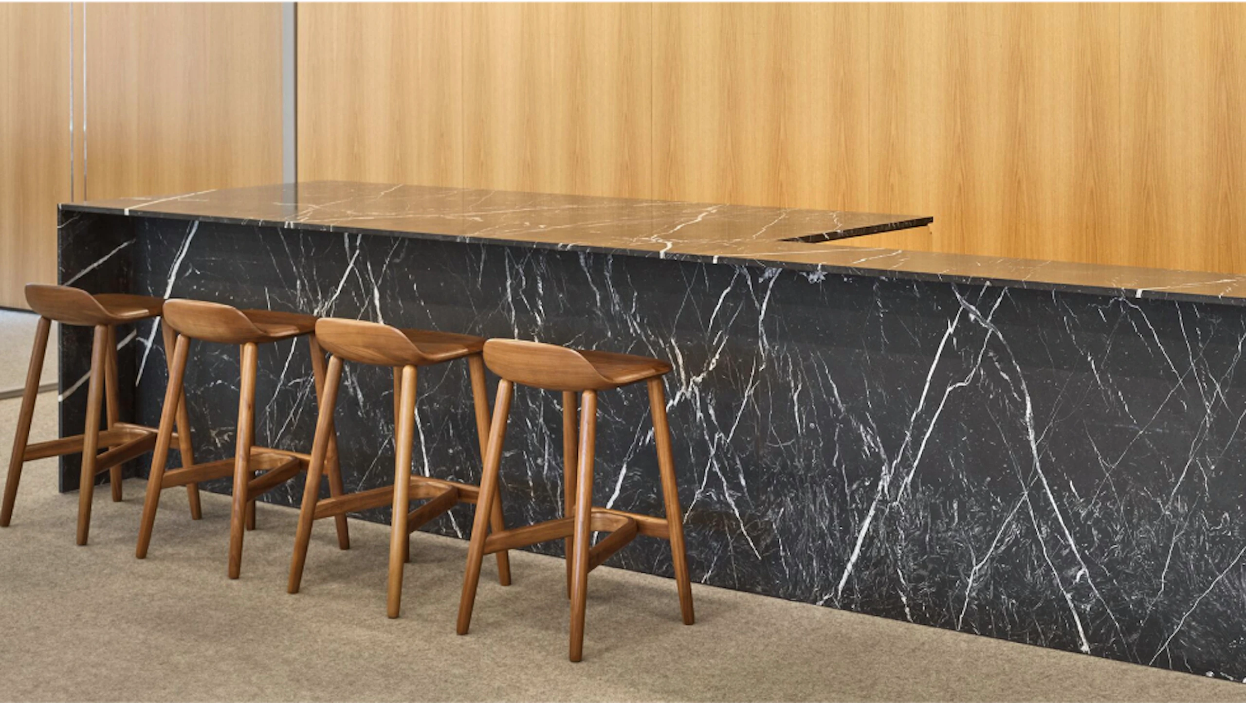Four brown counter-height stools at a dark grey and white counter