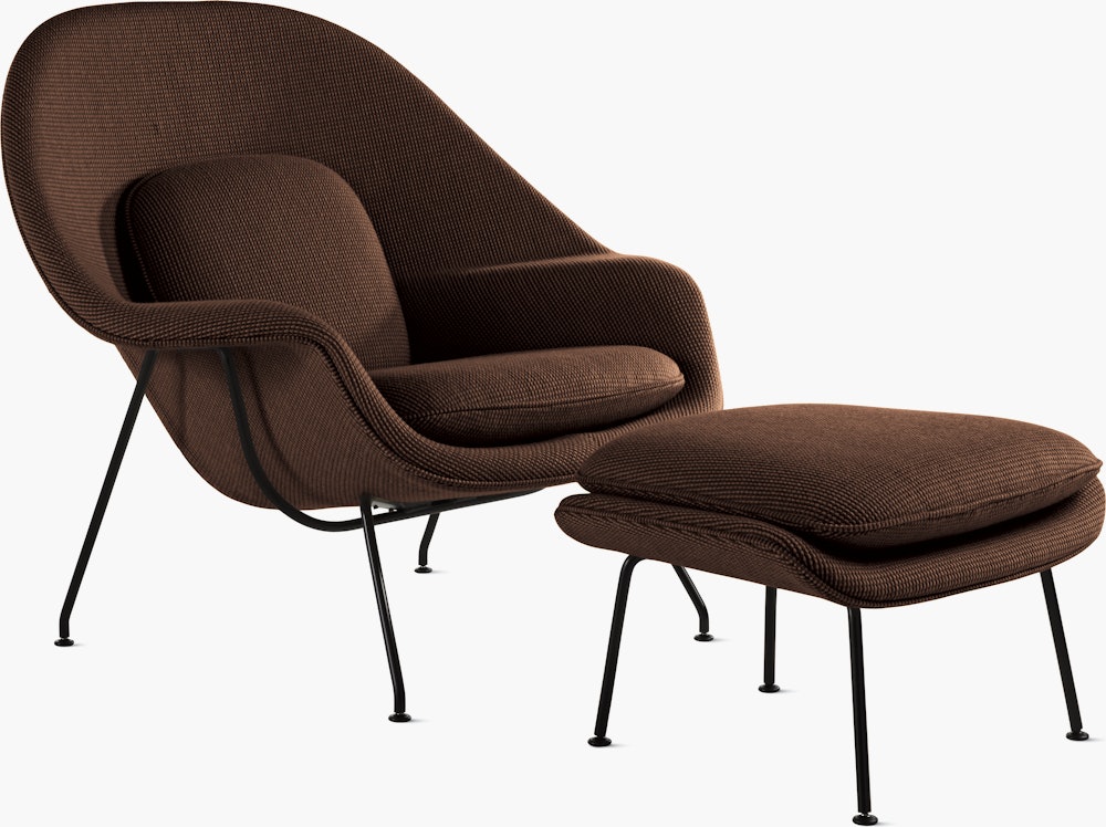 A brown Womb Chair & Ottoman viewed from an angle