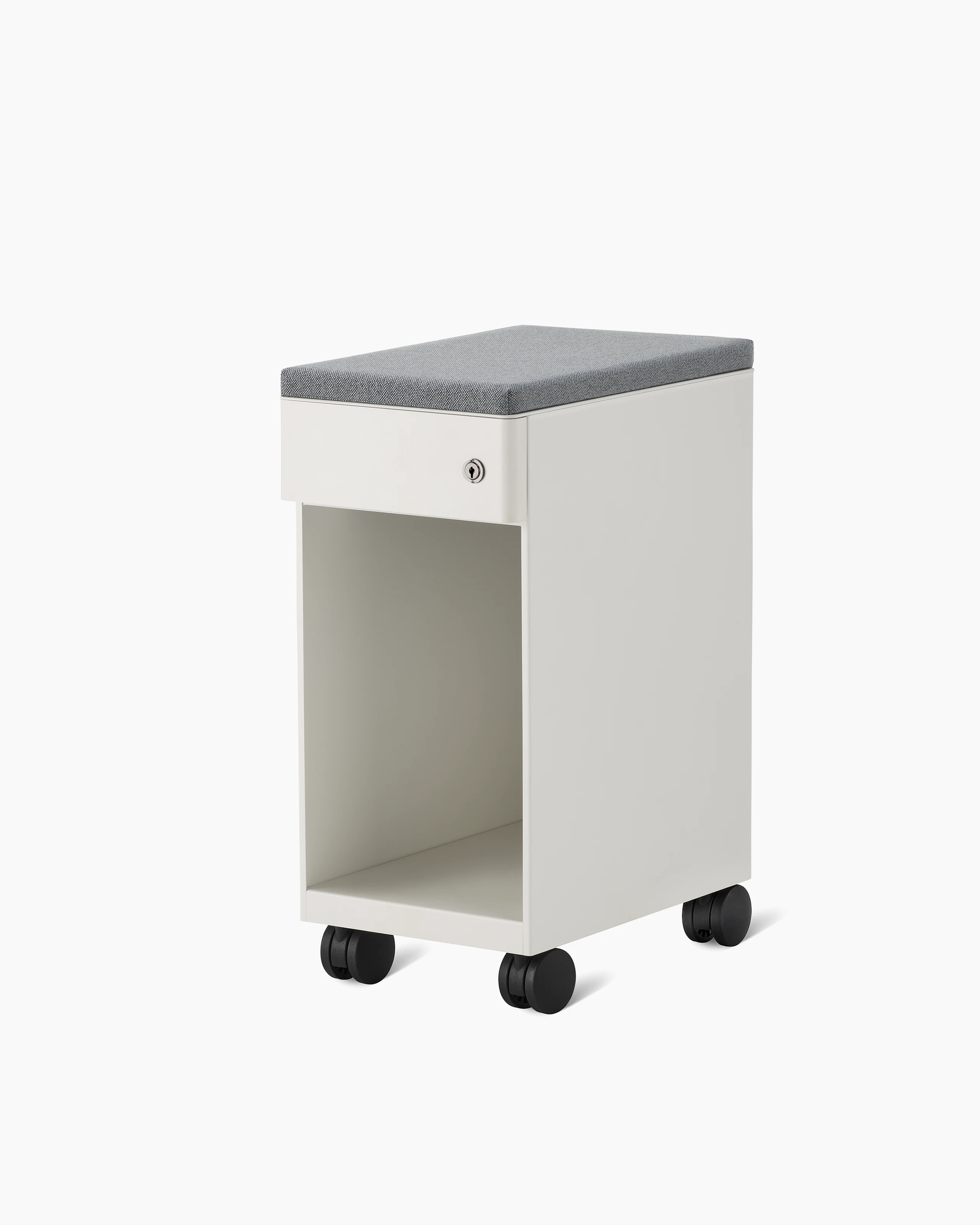 Slim, white storage pedestal on casters with a drawer and a lock, a gray cushion on top, and opening below drawer for storage.