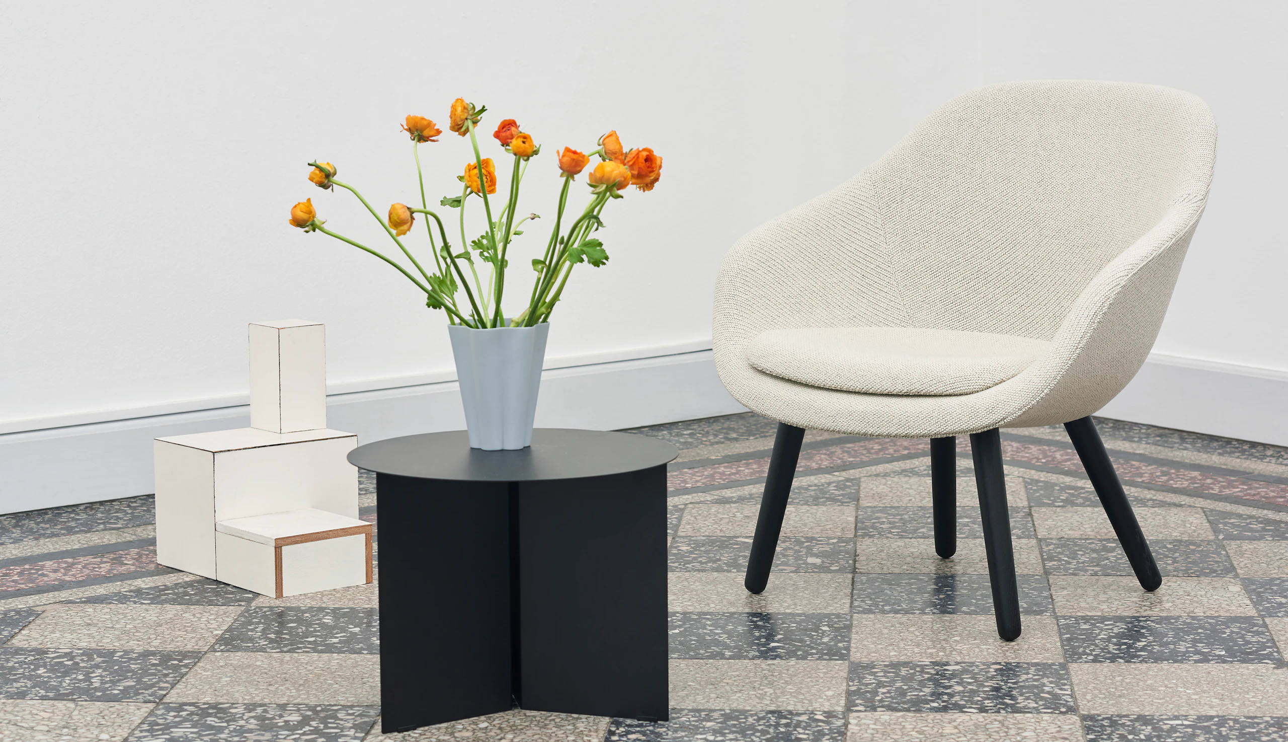 White About A Lounge Chair with black wooden base and round, black Slit Table.
