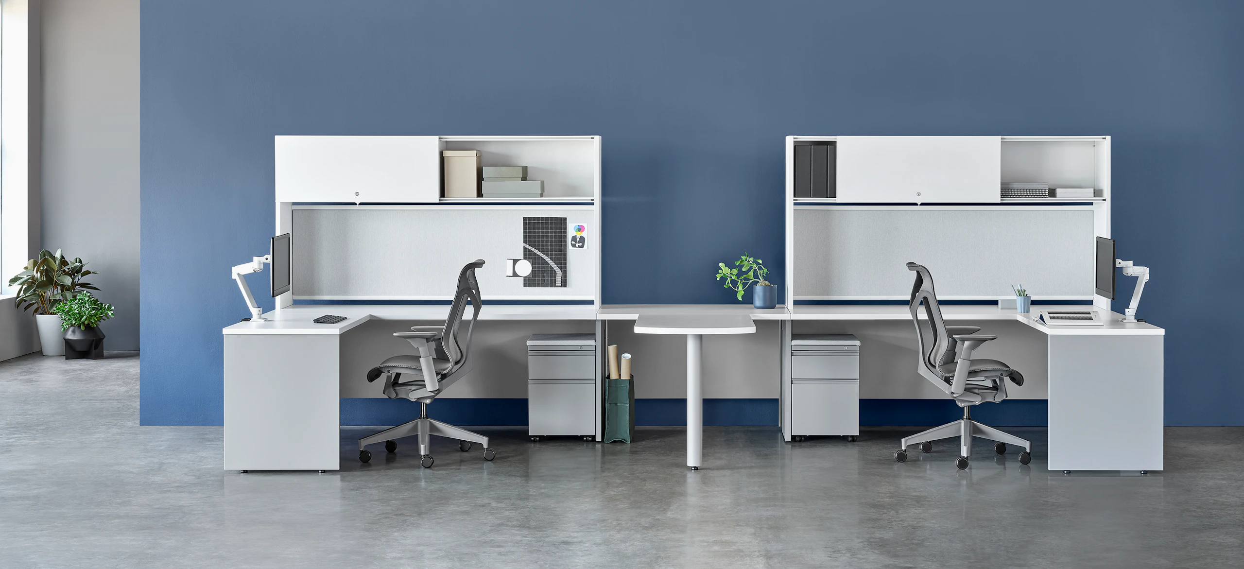White and gray Canvas Metal Desks with overhead storage, peninsula surface, and gray Cosm Chairs.