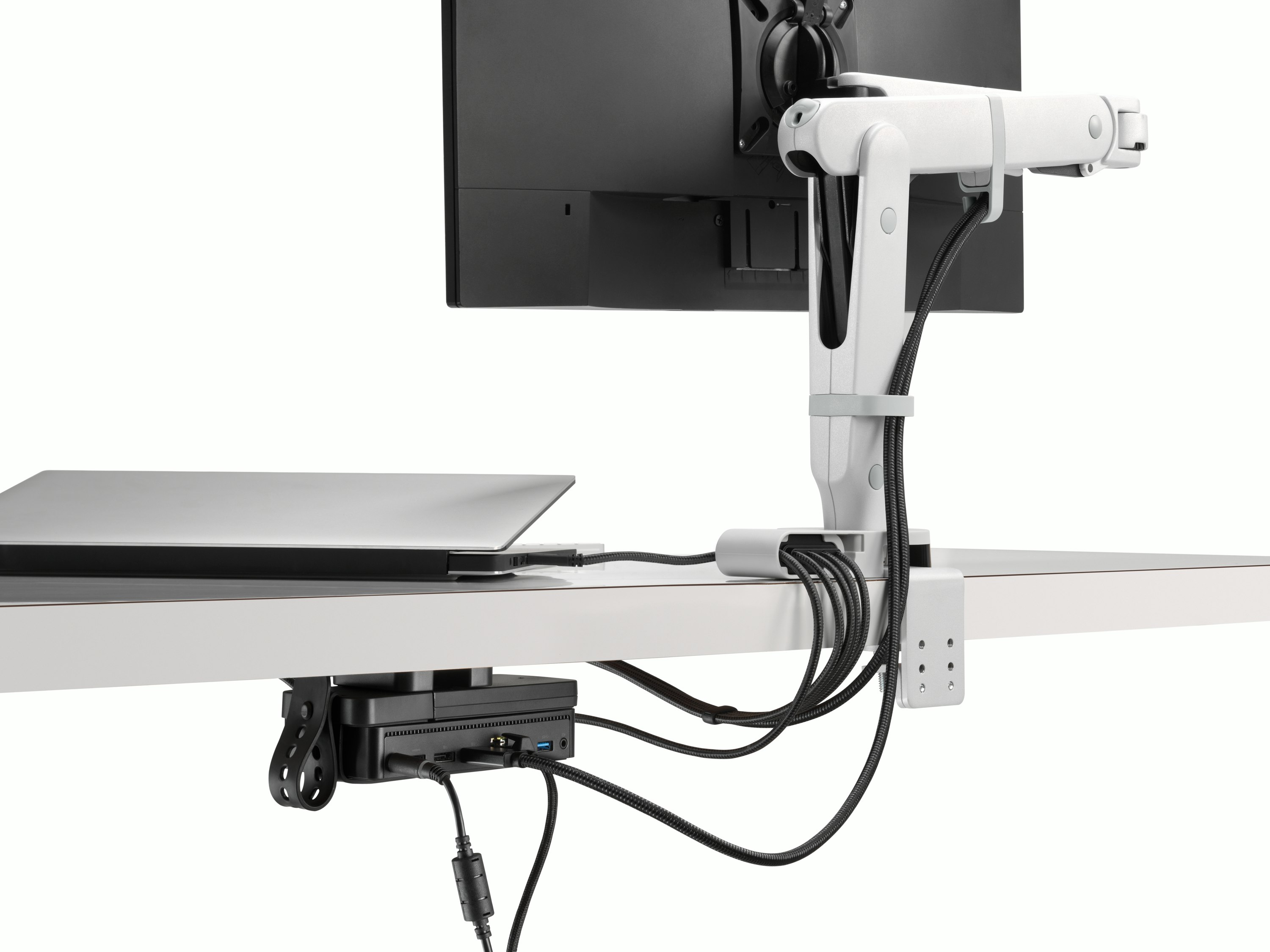 Back view of a monitor screen with power and data cables routed from the connected monitor arm and through the Ondo Connectivity Module and Loop Micro Mount under a desk.