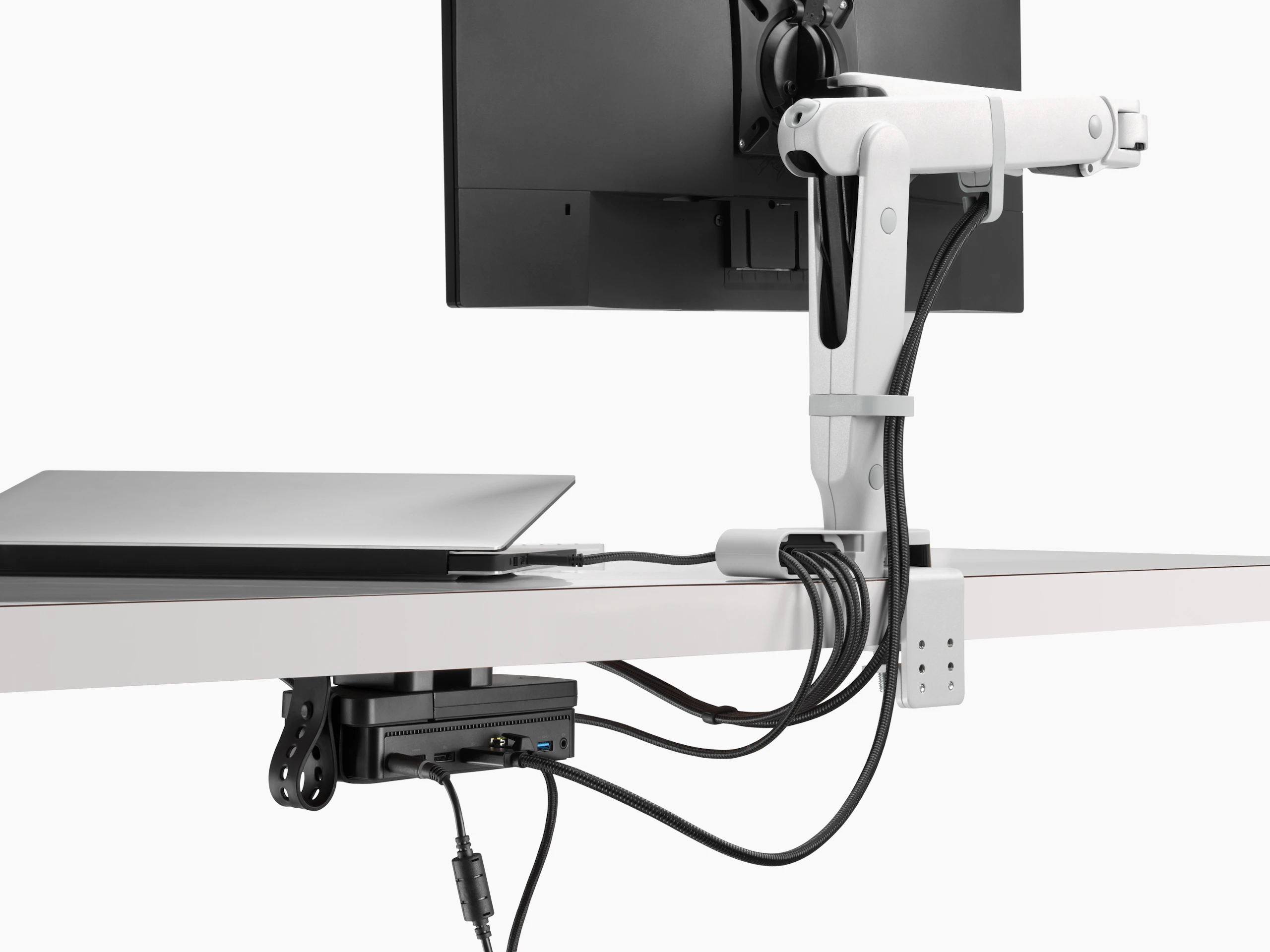 Back view of a monitor screen with power and data cables routed from the connected monitor arm and through the Ondo Connectivity Module and Loop Micro Mount under a desk.