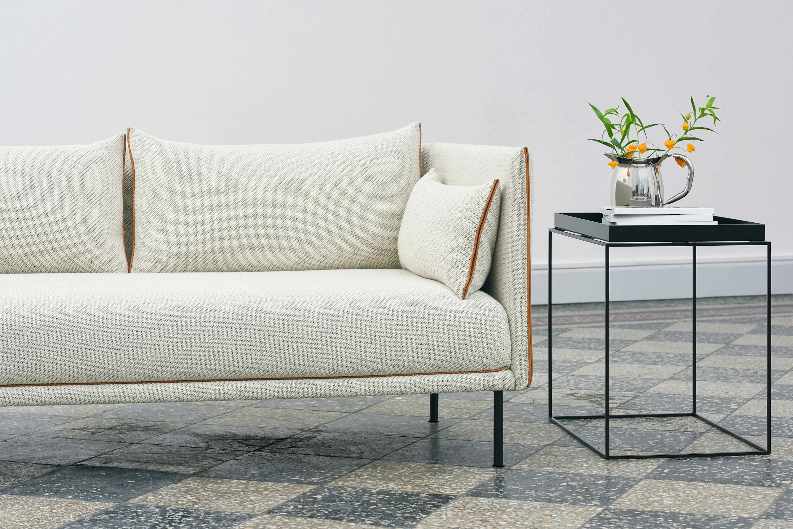Black, square Tray Side Table alongside off-white Silhouette Sofa.