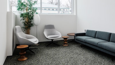 Group collaboration room in an academic research institute with two lounge chairs, a sofa, lamp, powered occasional table, and low stools.