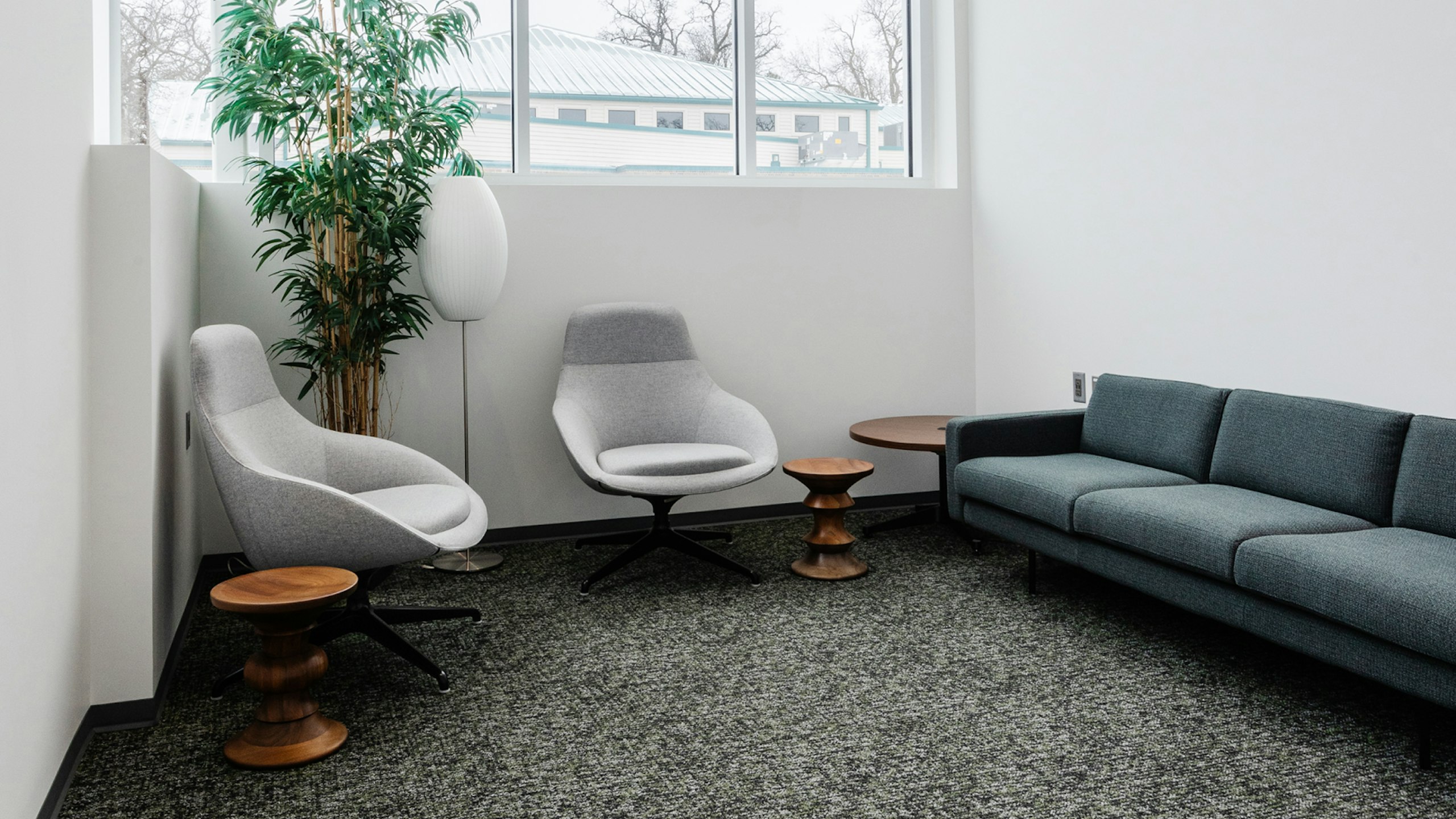 Group collaboration room in an academic research institute with two lounge chairs, a sofa, lamp, powered occasional table, and low stools.