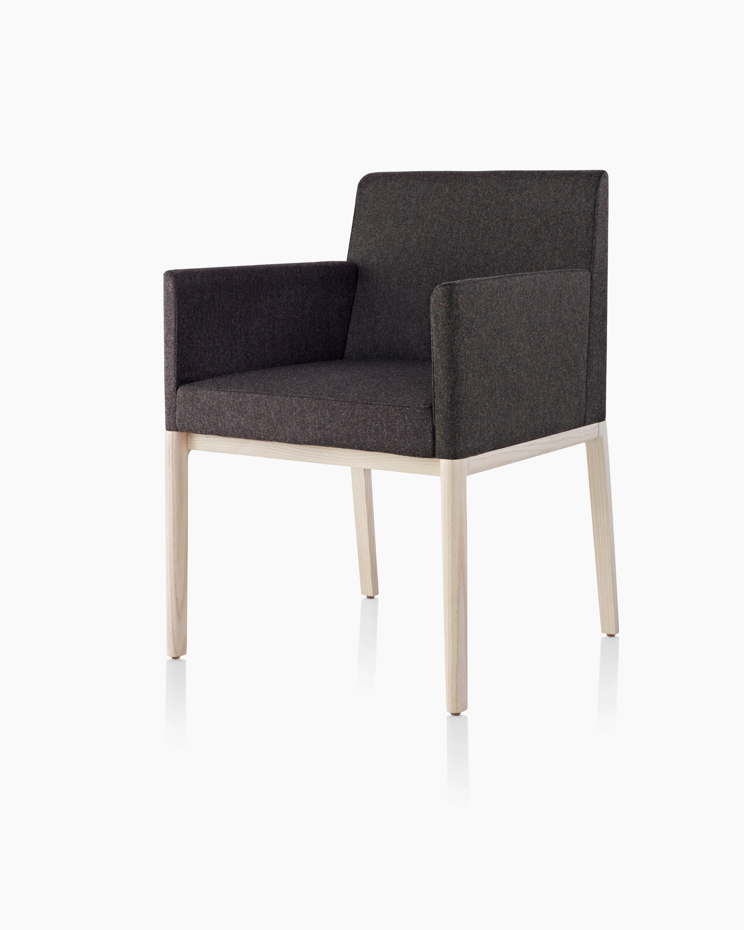 Angled view of a Nessel side chair with wraparound arms, showing the precision upholstery and wood craftsmanship.