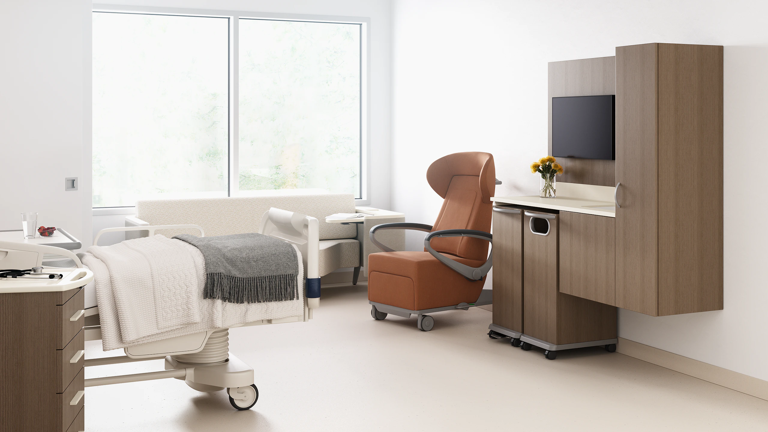 A patient room with a footwall of Mora casework with a trash cart and linen cart in medium brown wood finish, an Ava recliner in tan, a Palisade Flop Sofa in off white, a patient bed, with a Mora supply cart next to it.