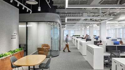 An office space with banks of workstations and conference rooms furnished with Herman Miller Cosm Chairs, Knoll Saarinen Executive Chairs, and NaughtOne Polly Chairs