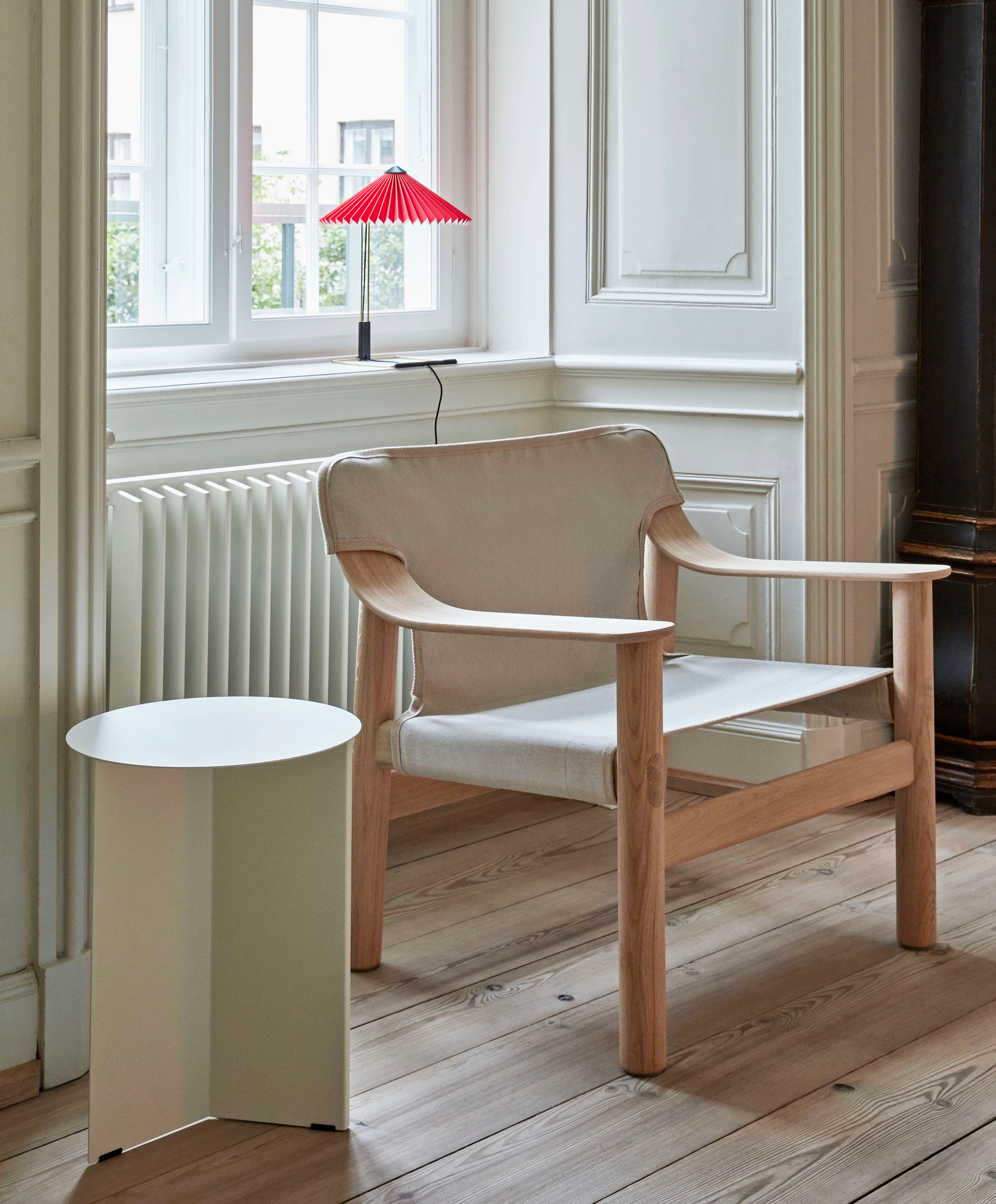 A tan Bernard Lounge Chair with a wood frame next to a Slit Table.