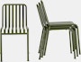 A Palissade Side Chair in olive green is beside a stack of three more chairs.
