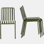 A Palissade Side Chair in olive green is beside a stack of three more chairs.