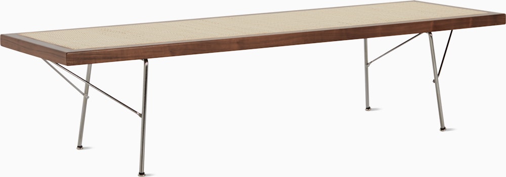 A Nelson Cane Bench with a walnut frame and metal legs, viewed at an angle.