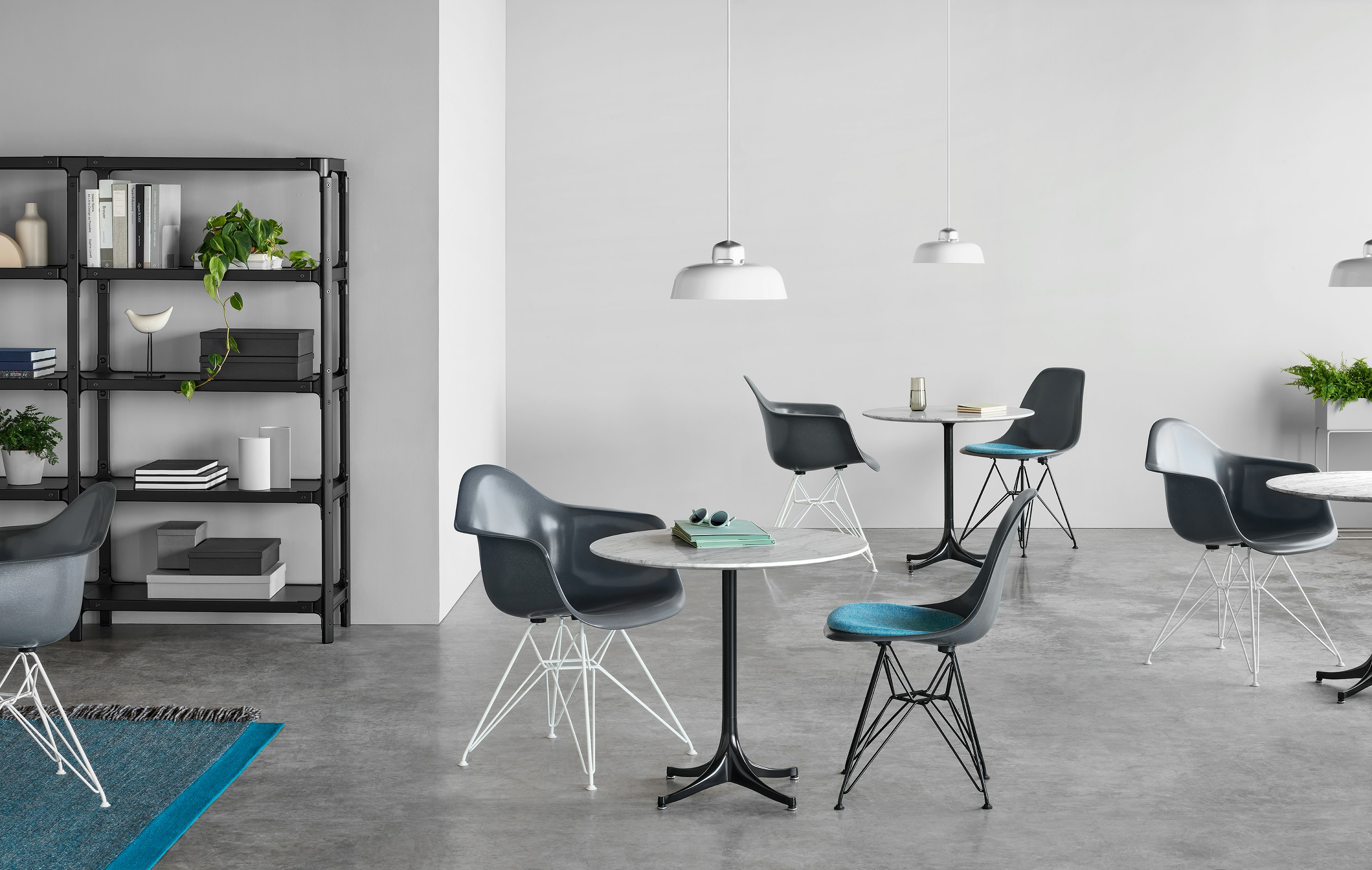 Gray Eames Molded Fiberglass Chairs arranged around Nelson Pedastal Tables in a cafe setting.