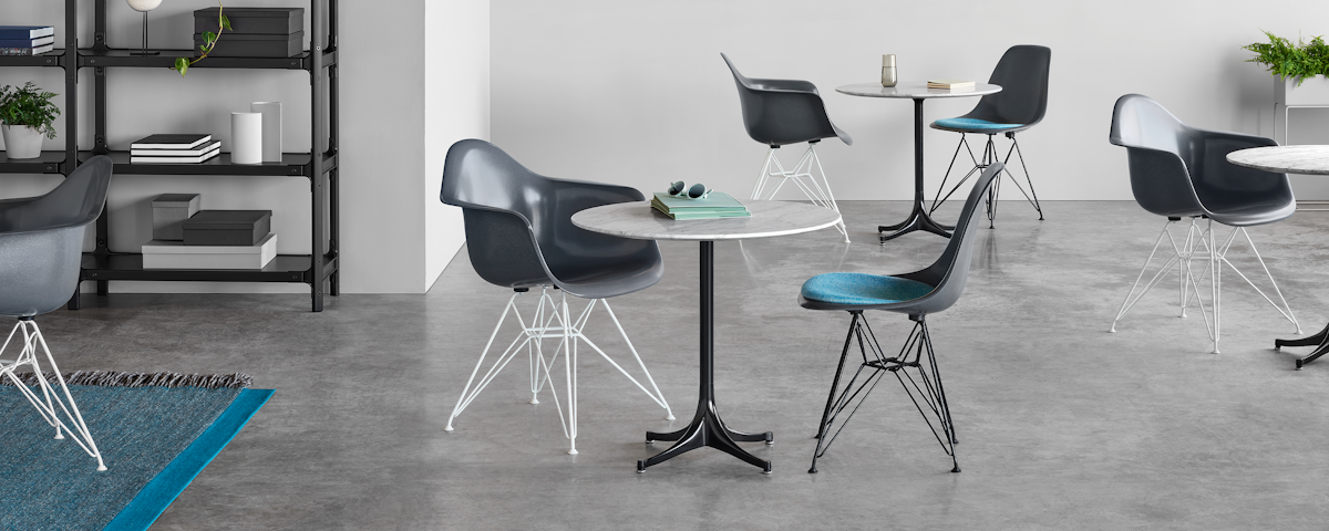 Gray Eames Molded Fiberglass Chairs arranged around Nelson Pedestal Tables in a cafe setting