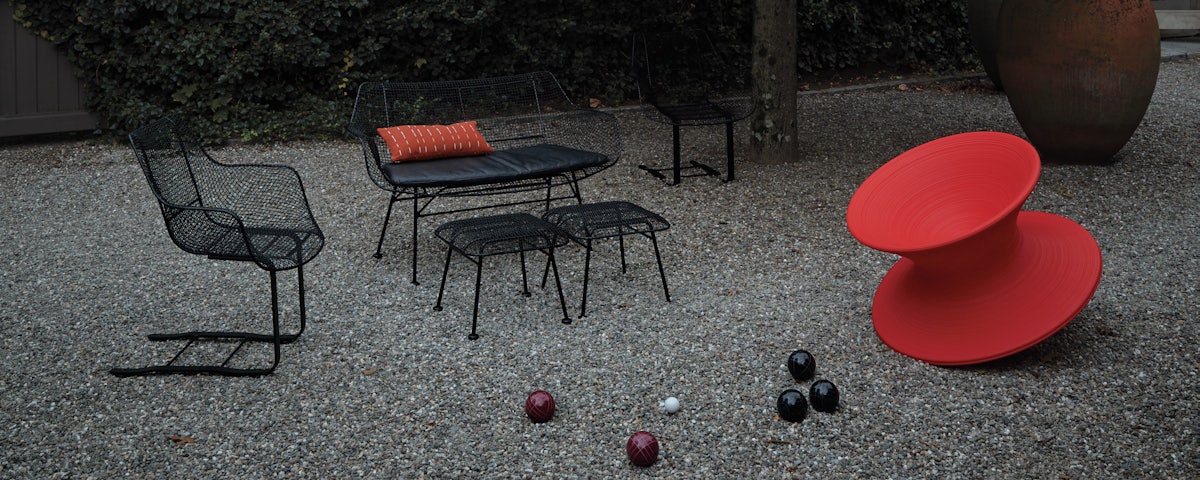 Sculptura Spring Chair, Sculptura Bench, and Sculptura Ottoman in a stone pebble courtyard