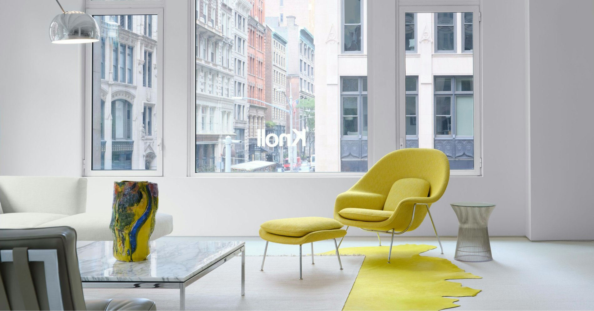 The Knoll showroom at 251 Park Avenue South in New York City featuring a marble coffee table, white sofa, and yellow Knoll Womb Chair and Ottoman