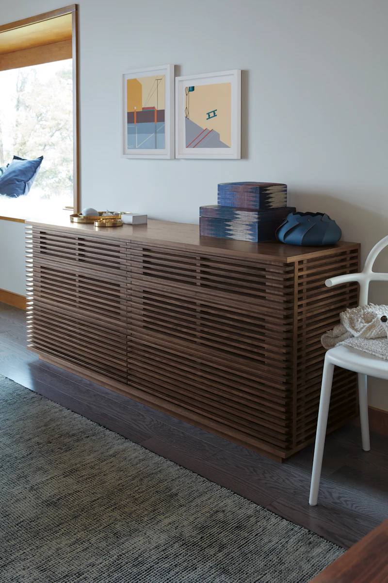 Long wooden slatted sideboard in living room with framed artwork above