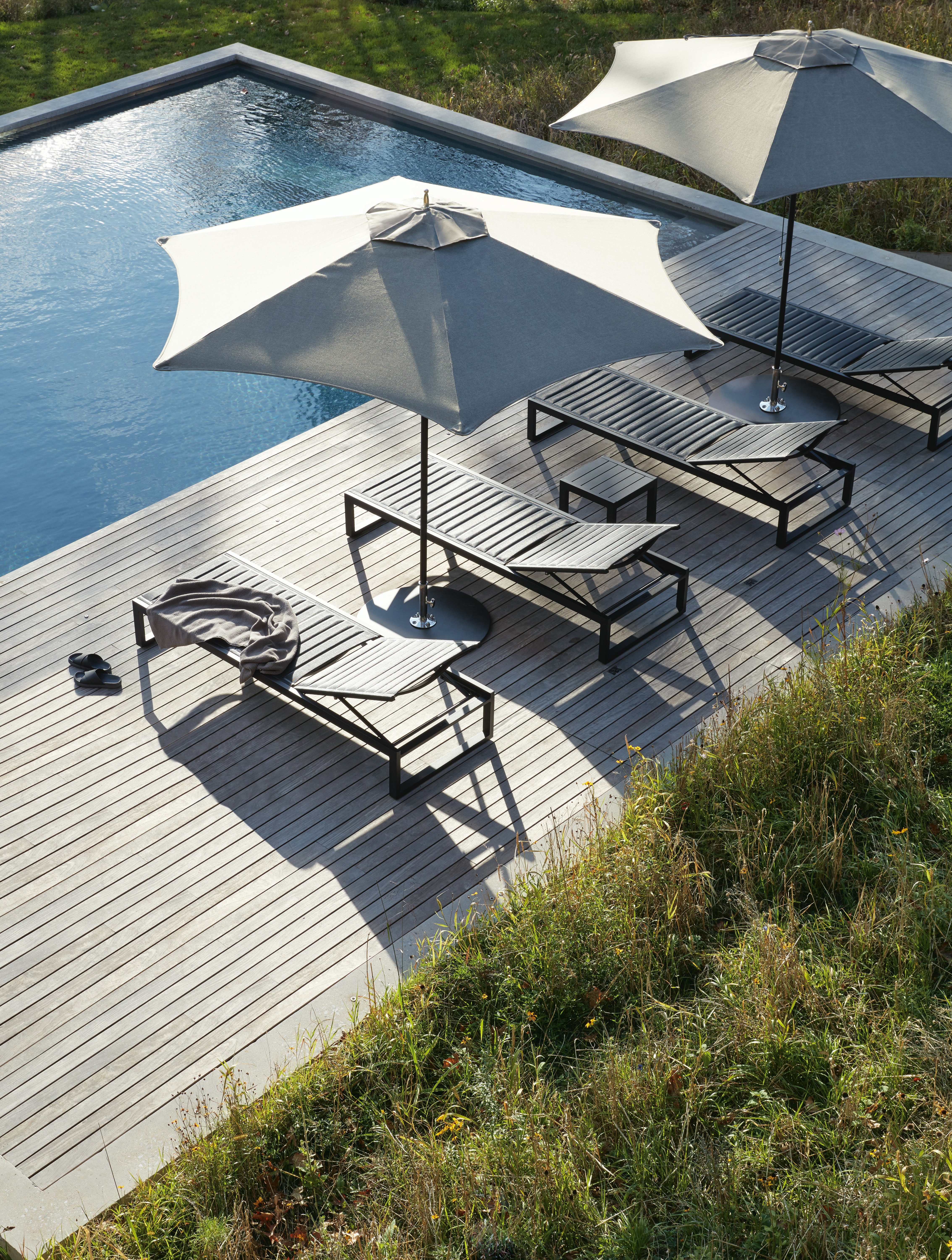 Tuuci Ocean Master Hexagon Umbrellas and EOS Chaise Lounge Chairs at a poolside setting