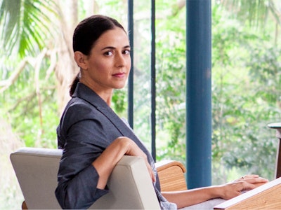 Architect and designer Sol Camacho seated in front of green foliage