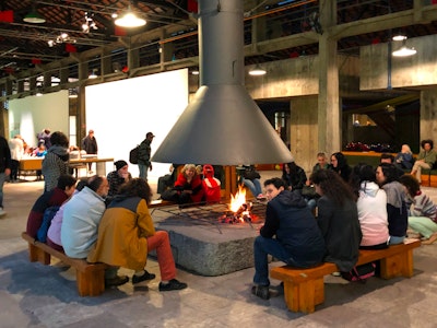 Groups of people seated around a large fireplace in the multi-use space at SESC Pompeia Factory