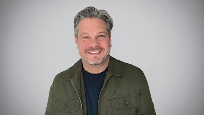 MillerKnoll VP of Global Research and Insights Ryan Anderson stands smiling while wearing a green jacket.