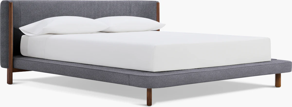 Close-up of a modern upholstered bed frame with light beige fabric and wooden legs.