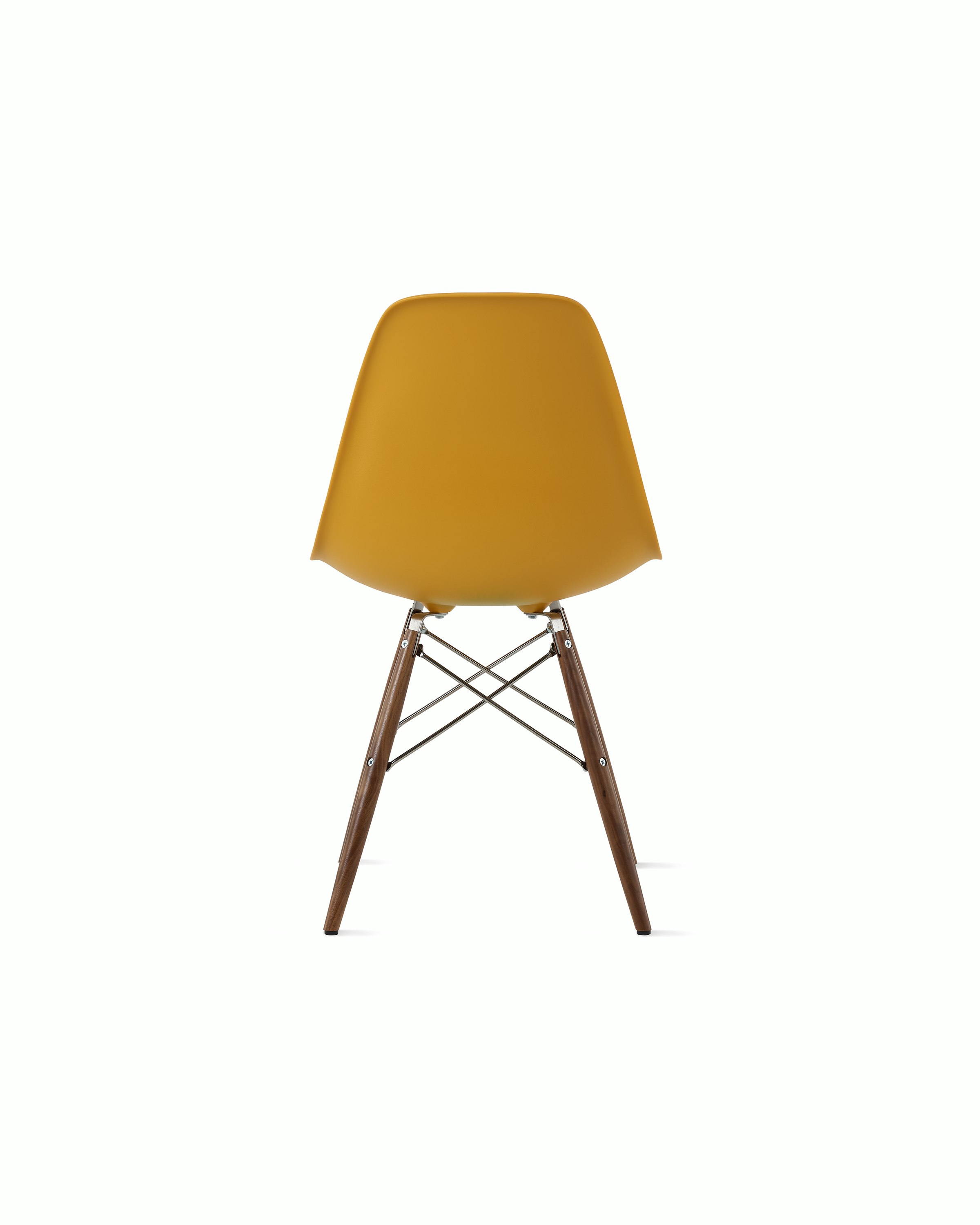 Back of deep yellow plastic shell chair on dowel-base legs.