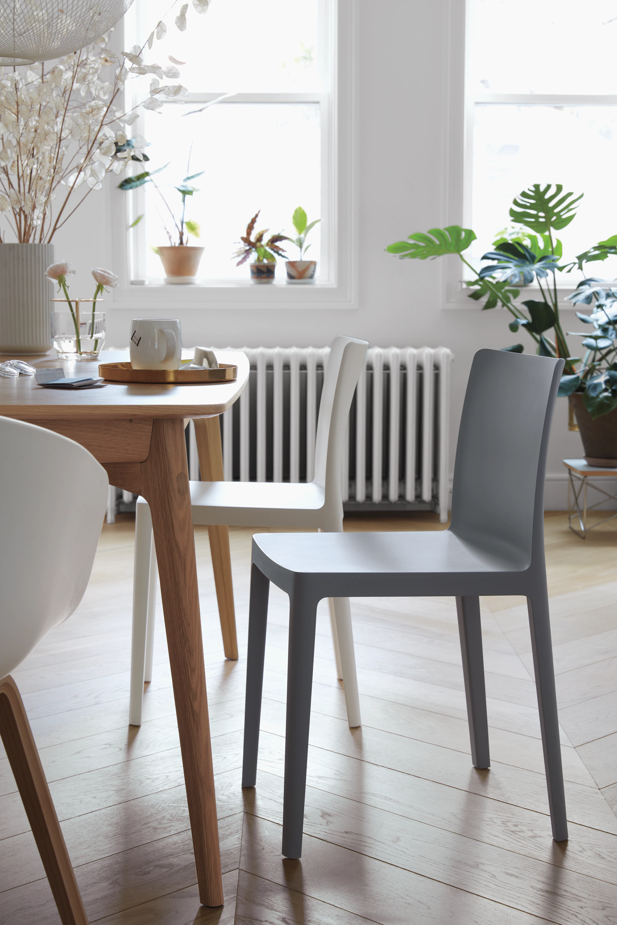 Two Élémentaire Chairs in cream white and blue-grey next to a dining table.