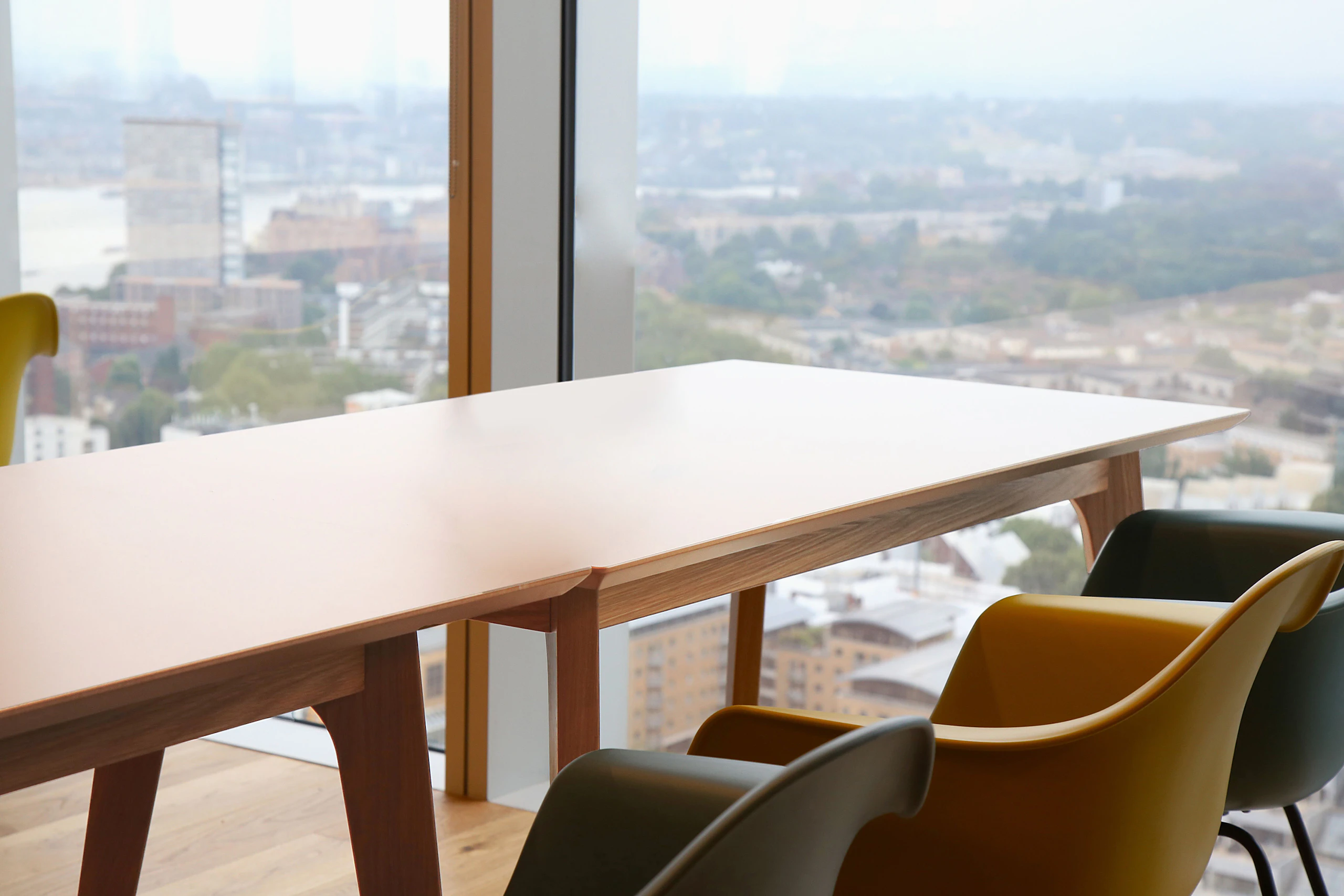 A white naughtone Dalby Conference Table in a high-rise conference room, Eames Molded Plastic Chairs by Herman Miller in the foreground.