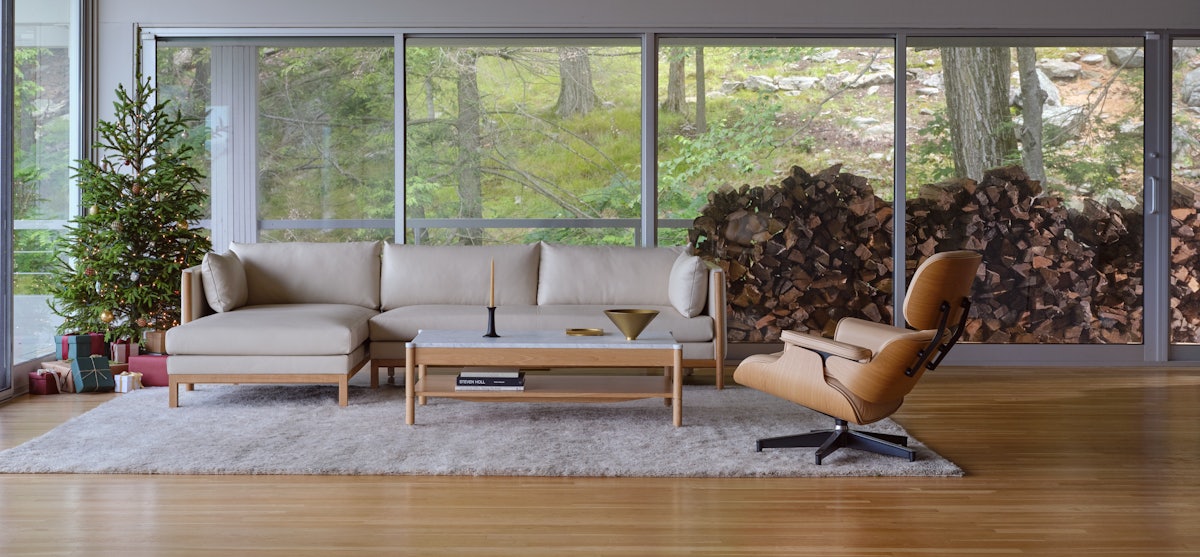 Emmy Sectional Chaise, Eames Lounge Chair and Ottoman, and Morrison Coffee Table in a living room setting with holiday decorations