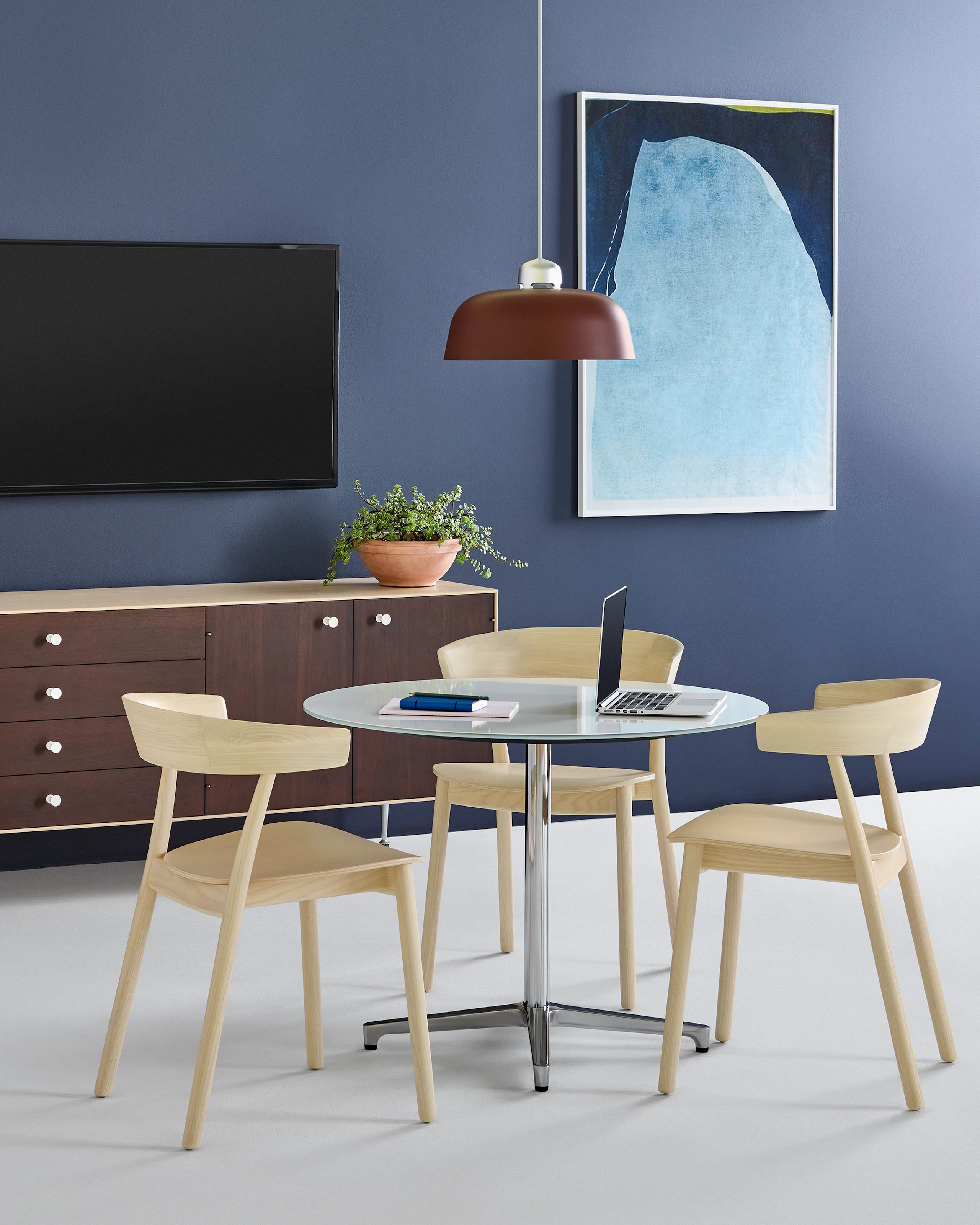 Three Leeway side chairs with a light wood finish complement a round Saiba occasional table with a white top and aluminum pedestal base.