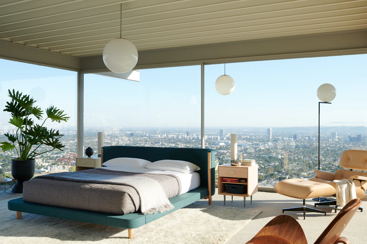 Bedroom with coral/red bedding and light wood furniture.