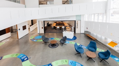 Large open area with lounge seating and occasional tables outside of a large meeting space.