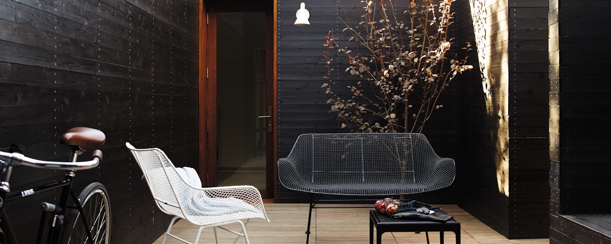 Sculptura Chair and Sculptura Bench in an outdoor courtyard setting