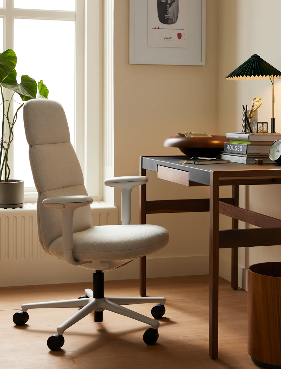 Bright yellow office chair at desk in a modern home office with plants and wooden furniture