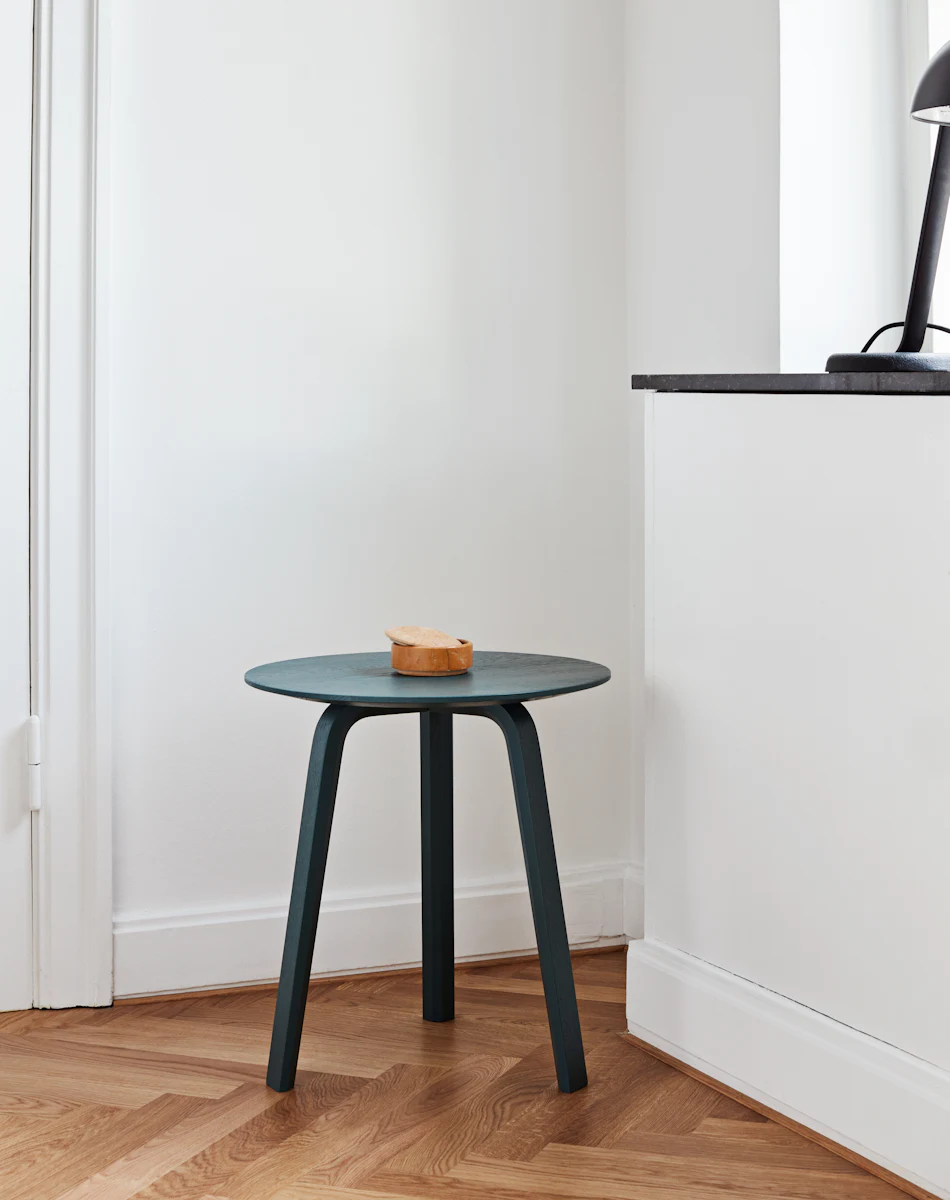Small round dark blue wooden stool with a small slice of bread on top, placed in a bright interior