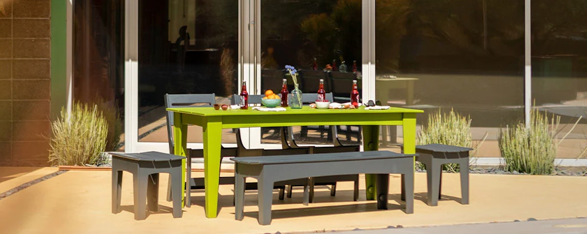 Alfresco Dining Table, Lollygagger Lounge Chairs, and Lollygagger Benches at a poolside setting