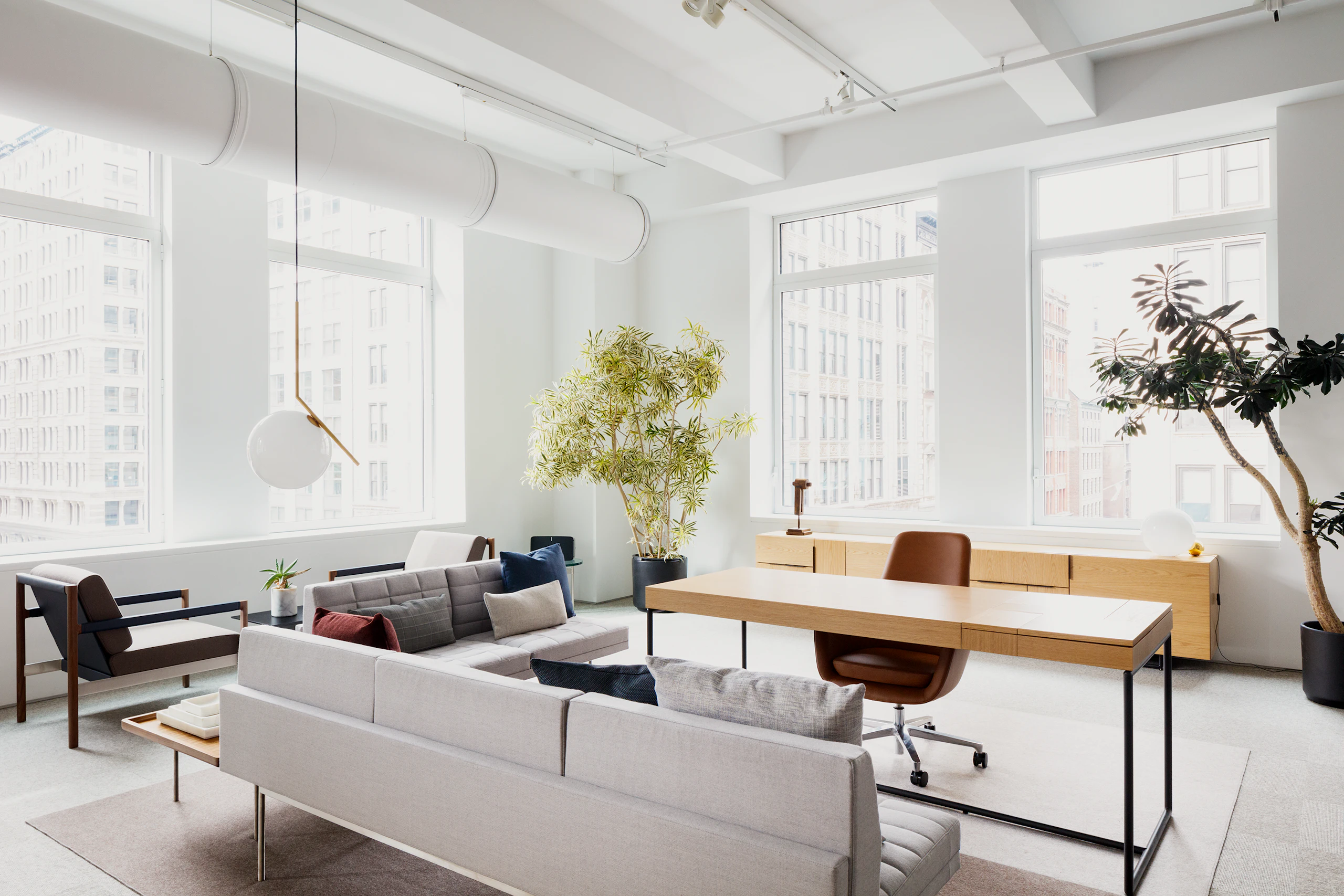 High vantage point, angled view of the Geiger Domino Desk in light oak wood and Tuxedo Component Sofa in light grey.