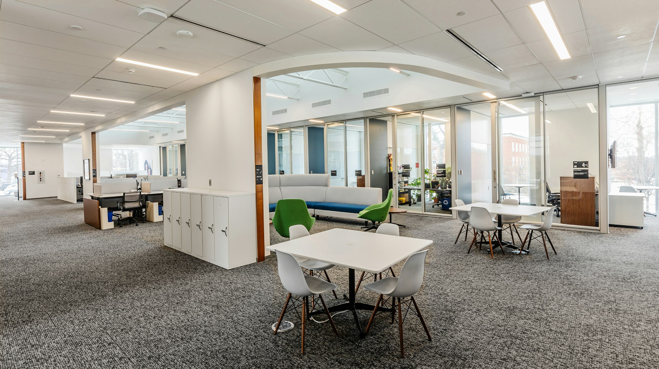Small group collaboration areas in an academic research institute with square tables and four chairs around them.