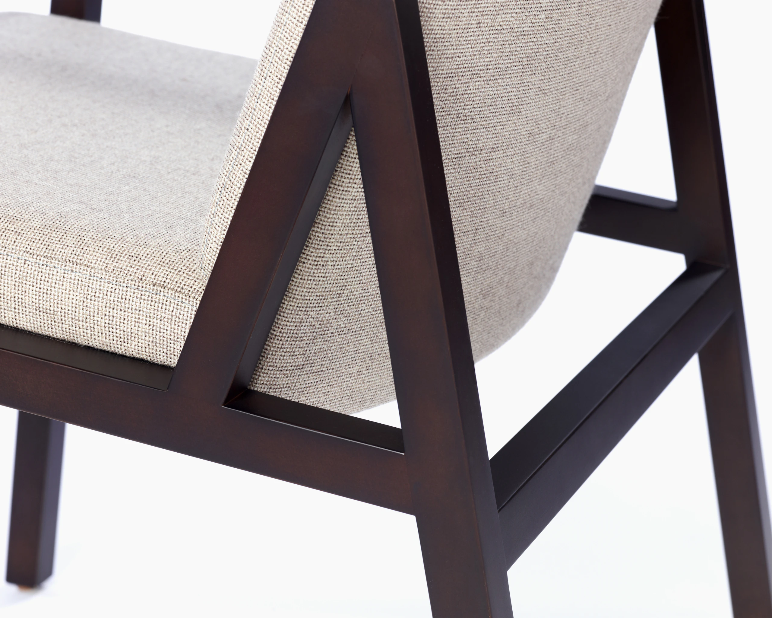 Partial view of an Ascribe Chair, showing the wood frame and upholstered seat and back.