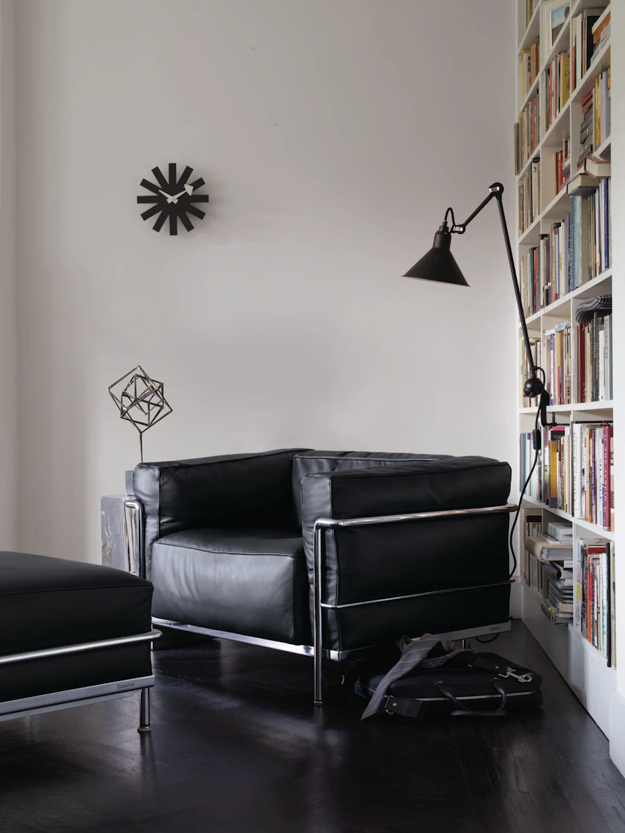Living room scene featuring black leather modular sofa set with metal frame and ottoman; contemporary interior.