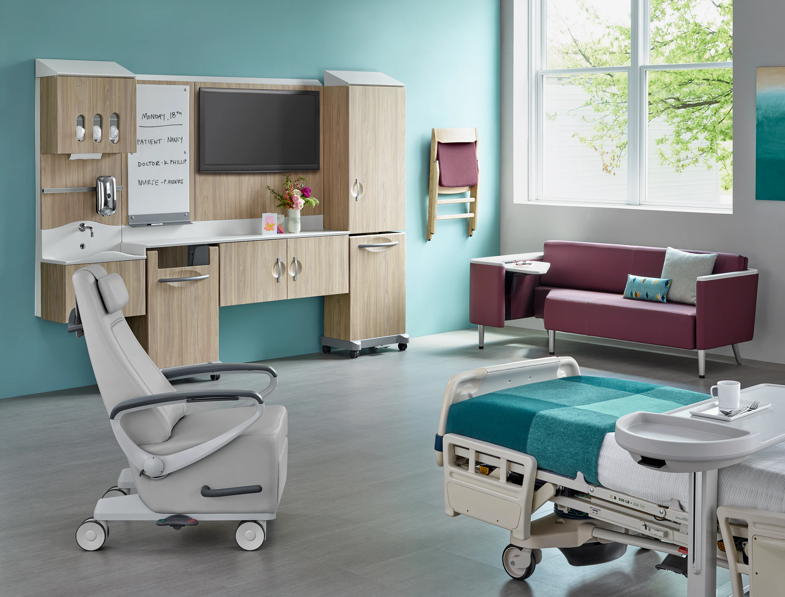 Patient room featuring Compass System Nemschoff Dex 2 Folding Chair, Nemschoff Palisade Flop Sofa, and Nemschoff Ava Recliner in a hospital setting.