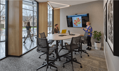 Two individuals having a discussion in a meeting space furnished with Herman Miller Setu Chairs